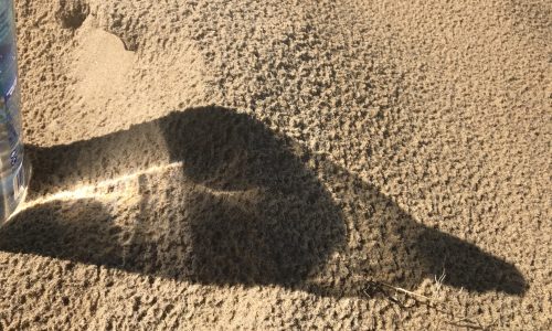 Light through bottle on the sand